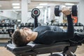 Handsome young man lying on exercise bench and lifting dumbbells at gym Royalty Free Stock Photo