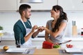 Handsome young man making the joke of asking his girlfriend to marry with a bell pepper in the kitchen at home.