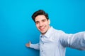 Handsome young man is making selfie and smiling on blue background Royalty Free Stock Photo