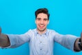 Handsome young man is making selfie and smiling on blue background Royalty Free Stock Photo