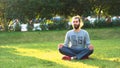 Handsome young man meditating on green grass. Concept. Man sitting on fresh green lawn in the city park on a summer Royalty Free Stock Photo