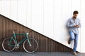 Handsome young man with mobile phone and fixed gear bicycle standing on a two-color modern wall Royalty Free Stock Photo