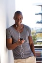 Handsome young man with mobile phone listening to music against wall Royalty Free Stock Photo