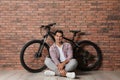 Handsome young man with modern bicycle near brick wall Royalty Free Stock Photo