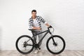 Handsome young man with modern bicycle near white brick wall Royalty Free Stock Photo