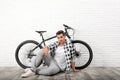 Handsome young man with modern bicycle near white brick wall Royalty Free Stock Photo