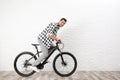 Handsome young man with modern bicycle near white brick wall Royalty Free Stock Photo