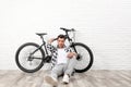 Handsome young man with modern bicycle near white brick wall Royalty Free Stock Photo