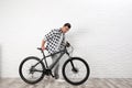 Handsome young  with modern bicycle near white brick wall indoors Royalty Free Stock Photo