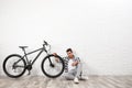Handsome young with modern bicycle near white brick wall indoors Royalty Free Stock Photo