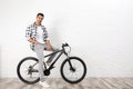 Handsome young man with modern bicycle near white brick wall Royalty Free Stock Photo