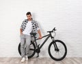 Handsome young man with modern bicycle near white brick wall Royalty Free Stock Photo