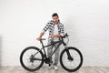 Handsome young man with modern bicycle  white brick wall indoors Royalty Free Stock Photo