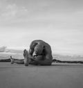 Handsome young man with naked torso doing stretching exercises on a rooftop