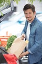 handsome young man packing groceries into car trunk outdoors Royalty Free Stock Photo