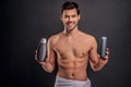 Handsome young man . Portrait of shirtless muscular man is standing on grey background with shampoo in hands. Men care