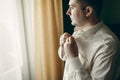 Handsome young man preparing for business meeting, putting on shirt, happy groom posing near window in hotel room before the Royalty Free Stock Photo