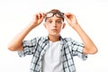 Handsome young man raises glasses on forehead in surprise, teen boy shocked, in Studio on white background