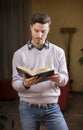 Handsome young man reading book at home in his living-room Royalty Free Stock Photo