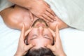Handsome young man receiving a head massage from a two masseurs Royalty Free Stock Photo