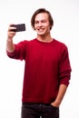 Handsome young man in red sweater holding camera and making selfie and smiling Royalty Free Stock Photo