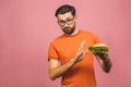 Handsome young man refusing unhealthy burger isolated over pink background. Diet concept. With copy space for text Royalty Free Stock Photo