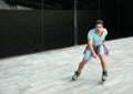 Handsome young man roller skating near glass building on city street Royalty Free Stock Photo