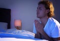 Handsome young man saying bedtime prayer in dark room Royalty Free Stock Photo