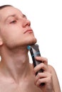 Handsome young man shaving with electric razor isolated over white background and looking at camera Royalty Free Stock Photo