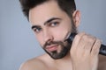 Handsome young man shaving with electric trimmer on grey background, closeup Royalty Free Stock Photo