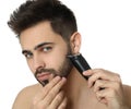 Handsome young man shaving with electric trimmer on white background Royalty Free Stock Photo