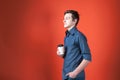 Handsome young man in shirt with rolled sleeves holding paper cup with coffee and hand in pocket, looking away Royalty Free Stock Photo