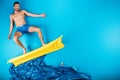 handsome young man in shorts smiling at camera while standing on inflatable mattress Royalty Free Stock Photo