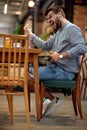 Handsome young man siting in cafe, playing music and dancing to it. Cafe background