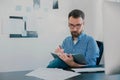 Handsome young man sits in his office while working on business project looks satisfied, takes notes to his agenda, work Royalty Free Stock Photo