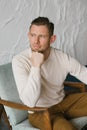 Handsome young man sitting in armchair indoors Royalty Free Stock Photo