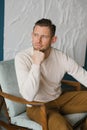 Handsome young man sitting in armchair indoors Royalty Free Stock Photo