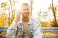 Handsome young man sitting on a bench in the autumn park Royalty Free Stock Photo