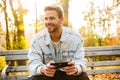 Handsome young man sitting on a bench in the autumn park Royalty Free Stock Photo