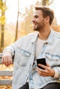 Handsome young man sitting on a bench in the autumn park Royalty Free Stock Photo