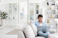 Handsome young man sitting on the couch In a living room with laptop Royalty Free Stock Photo