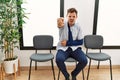 Handsome young man sitting at doctor waiting room with arm injury pointing displeased and frustrated to the camera, angry and Royalty Free Stock Photo