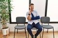 Handsome young man sitting at doctor waiting room with arm injury pointing fingers to camera with happy and funny face Royalty Free Stock Photo