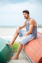 Handsome young man sitting on a fishing boat by sea Royalty Free Stock Photo