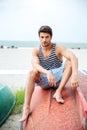 Handsome young man sitting on a fishing boat by sea Royalty Free Stock Photo