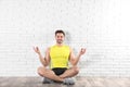 Handsome young man sitting on floor and practicing zen yoga Royalty Free Stock Photo