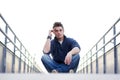 Handsome young man sitting between handrails in walkway