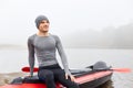 Handsome young man sitting on his canoe after rowing on kayak, happy sportsman having rest after long hours padding, wearing Royalty Free Stock Photo