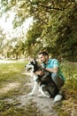 Handsome young man sitting with his dog in the park. Royalty Free Stock Photo