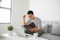 Handsome Young Man Sitting on the Living Room Couch, Writing Some Notes While Looking at his Laptop Computer Royalty Free Stock Photo